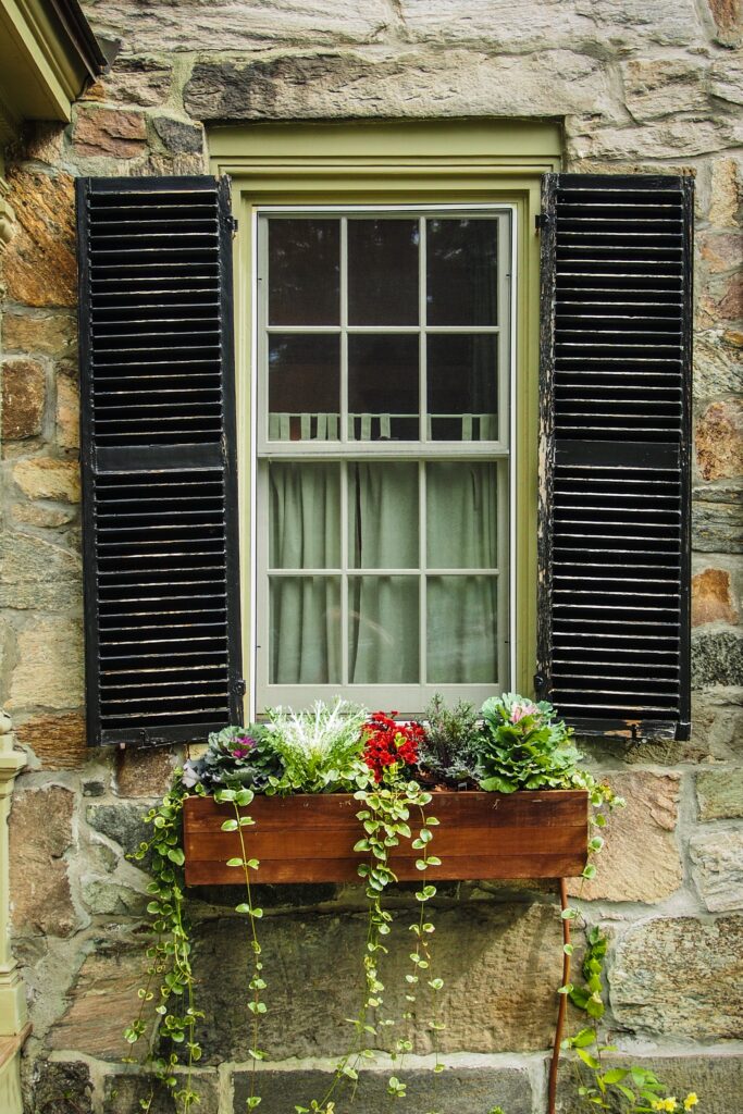 old stone house with window box full of fall flowers